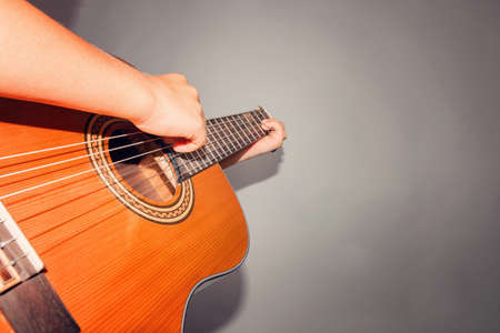Guitar and strings, man's hand on a gray background in the studio, wide angle photo.