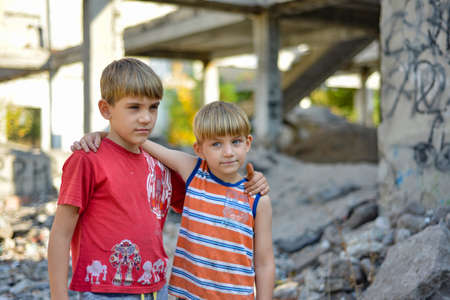 Two brothers are standing in an embrace against the backdrop of an unfinished and abandoned building, a concept of the life of street children of orphans.の写真素材