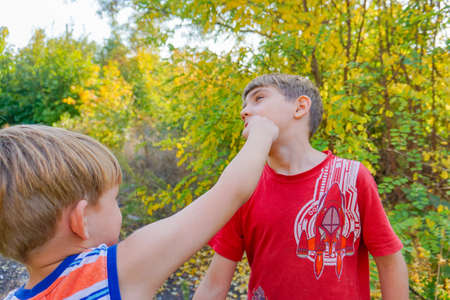 Two boys fight, one hits the other with his fist in the face.     