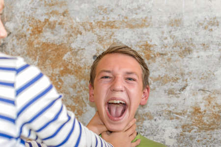 The girl strangles the boy, and he raised his hands up and can not breathe.  Production photo.の写真素材