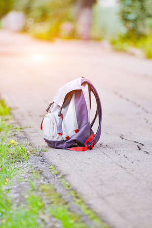 The backpack lies on the road, near the curb, the concept of traveling alone.