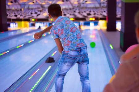 A boy throws balls at a bowling alley, knocking down pins.の写真素材