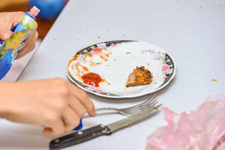 Man eats meat with a knife and fork on an empty plate.の写真素材