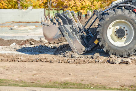 A bulldozer at a construction site removes unnecessary garbage with a bucket.