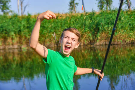 A fishing boy is trying to eat a caught fish for fishing rod.の写真素材