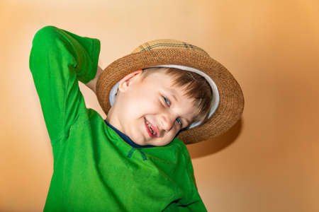 Joyful and happy boy in a straw hat and green clothes smiling and looking at the camera.の写真素材