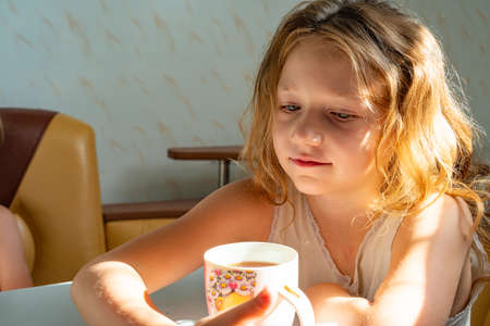Teen girl drinks coffee at home in the kitchen.の写真素材