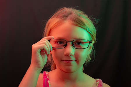 The girl in glasses on a black background holds glasses by the frame.の写真素材