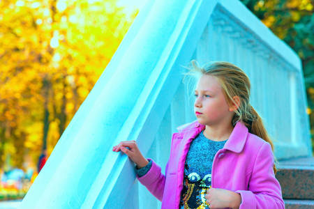 A girl in a lilac coat on white marble steps.