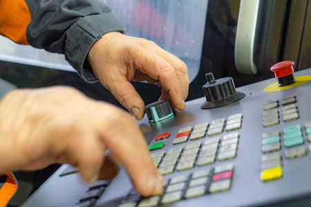 The control panel of a CNC machine, a worker writes a program for processing parts on a machine by cutting.の写真素材