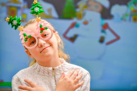 A joyful and happy girl in New Year's holiday glasses looks away while waiting for an amazing gift.の写真素材