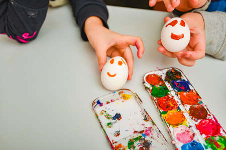 Painted eggs under the face by children with watercolor paints.の写真素材
