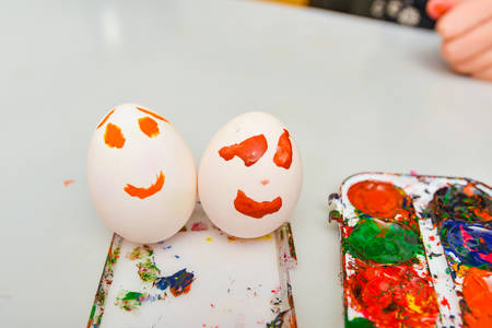 Two eggs with a painted face lie next to watercolors after art.の写真素材