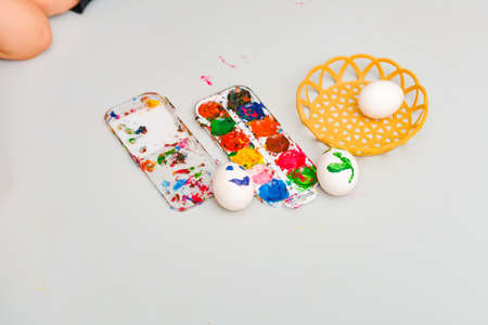 Two eggs with a painted face lie next to watercolors after art.の写真素材