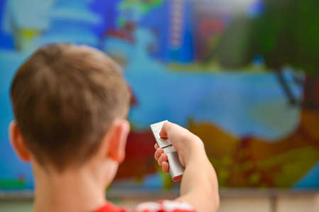 A man watches TV and directs the remote control to the screen.の写真素材