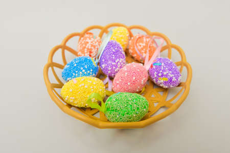 Easter colored eggs lie in a straw plate.