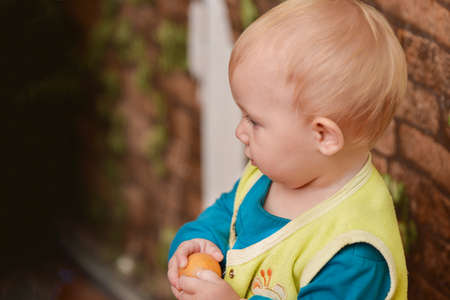 A small child is standing near an old brick wall.の写真素材