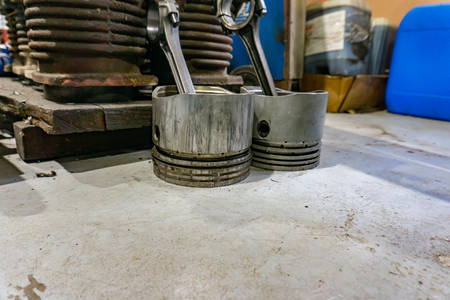 Piston with connecting rod next to internal combustion engine disassembled