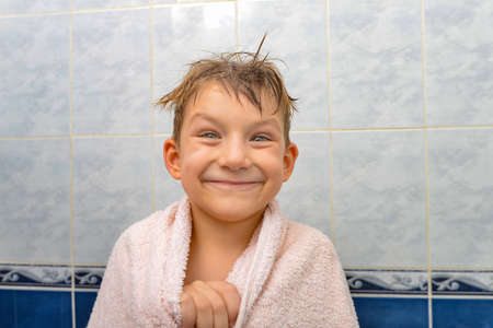 A boy in the shower wrapped in a towel, a joyful child after bathing.