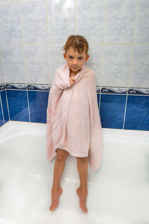A boy in the shower wrapped in a towel, a joyful child after bathing.の写真素材