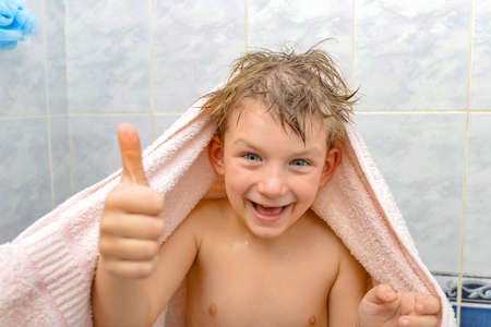 A boy in the shower wrapped in a towel, a joyful child after bathing
