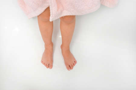 Baby feet in the bathtub, baby in a pink towel in the bathroomの写真素材