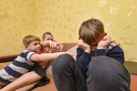 Children humiliate the boy and poke a finger at him in protest of communication.の写真素材
