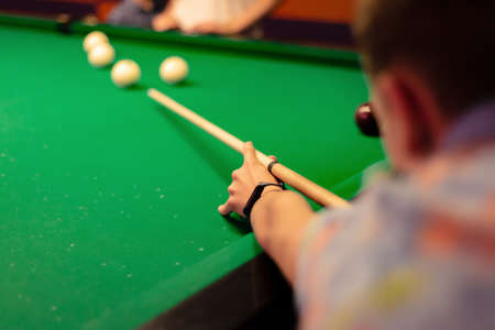 A man plays billiards and hits the ball with a cue, driving him into a pocket. Billiard sports.の写真素材
