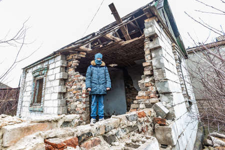 A boy in a ruined house, a teenager was left homeless as a result of military conflicts and natural disastersの写真素材