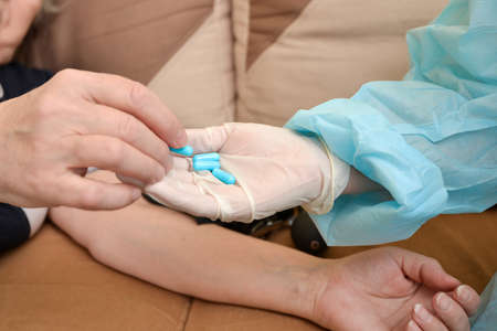 A sick patient takes medicine and pills from the hands of the attending physician