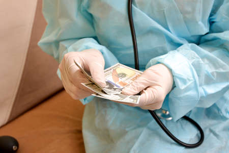 The doctor recounts the money that he took from the patient for the appointmentの写真素材