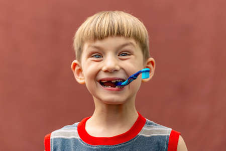 Joyful child with a toothbrush in his mouth wide open looking at the camera