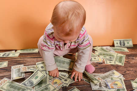 A small child sits on a heap with money. The concept of wealth and financial independence