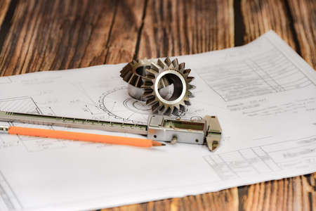 Bevel gear, vernier caliper and pencil on a technical drawing, concept of design and engineering productionの写真素材