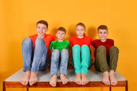 Four children squatting barefoot, a bright colorful juicy photo of teenagers sitting in colored clothesの写真素材