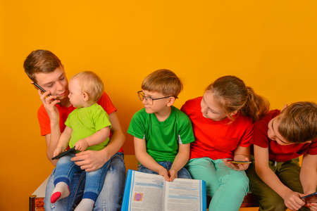 The older brother is talking on the phone, and the other children are looking at him.の写真素材