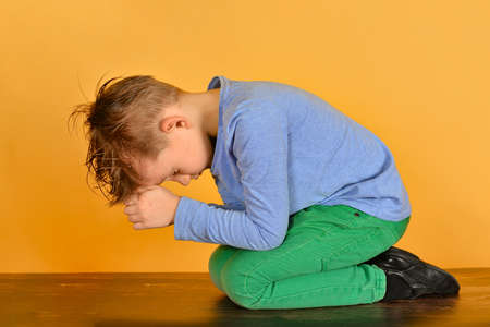The boy bowed in prayer before God. The child is kneeling in the prayer of repentance before the Supreme Creatorの写真素材