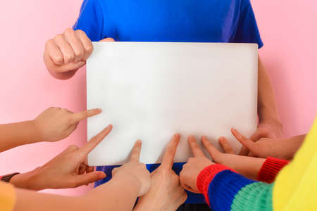 The boy holds in his hand a poster with an empty place, children show a finger on the textの写真素材