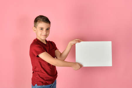 The boy holds a blank poster for inscriptions and advertising.の写真素材