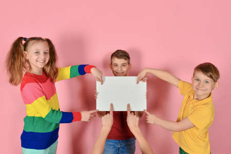 Two boys and a girl are holding a blank poster for inscription and text.