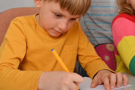 The boy writes with a pen in a notebook, the child is studying science.