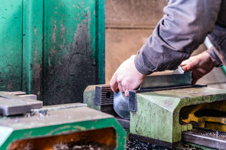 The worker sets the metal workpiece in a vice for processing on a CNC milling machine.