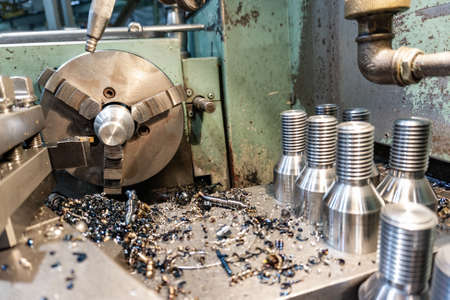 Bolt threading on a lathe in a machine shop, finished products on a machine bed.の写真素材