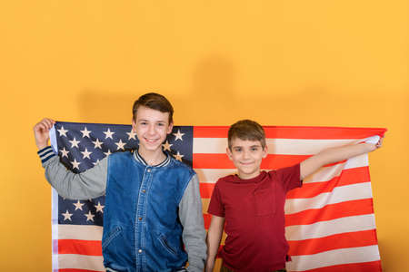 Two teenage brothers are standing against the backdrop of the American flag, young scouts are...