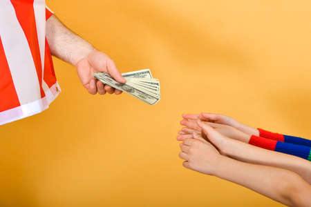 The hand of a man flying the American flag hands money to children’s hands, the concept of...