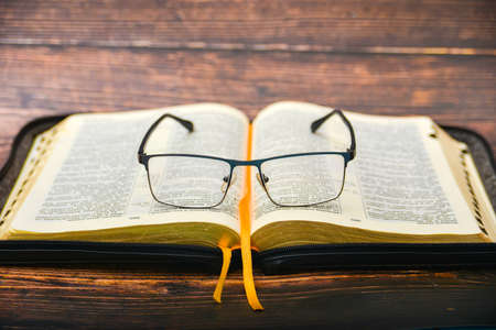 The Bible and glasses, glasses for sight lie on the opened Bible of a gift issue with gilded pages.の写真素材