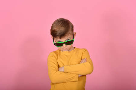 Glamorous and stylish boy posing for the camera, model in sunglasses, in yellow clothes in the studio on a pink background.の写真素材