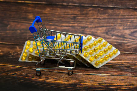Empty consumer trolley on yellow drugs background on brown wooden background.の写真素材