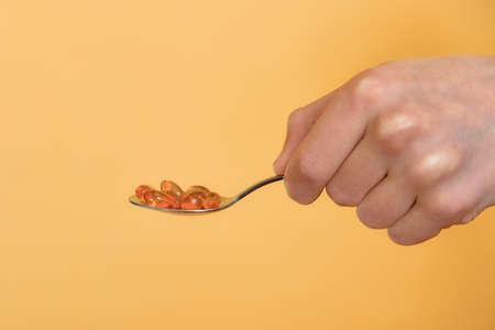 Capsules with fish oil lie in a spoon, taking medications.の写真素材