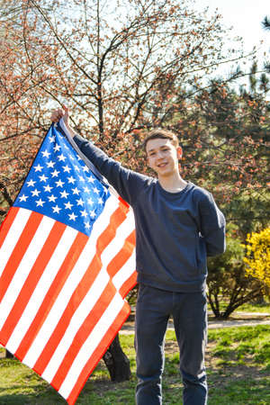 A teenage patriot raised his hand with the American flag to the top as a symbol of US victory and patriotism.の写真素材